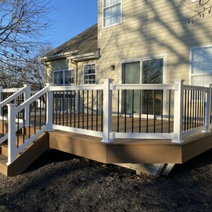 Photo of new deck with white railing, black balusters, and deck steps