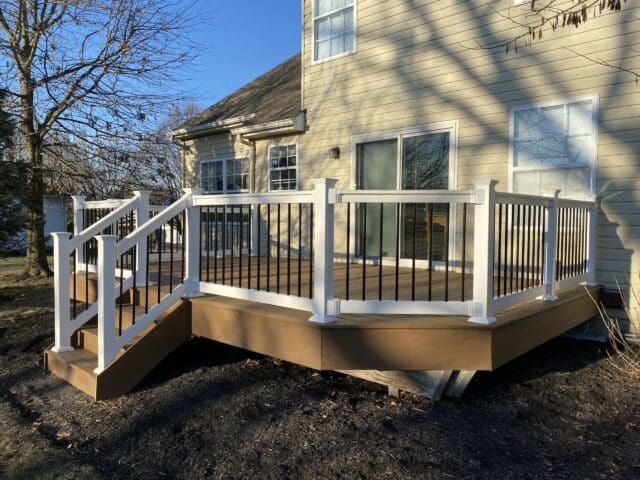 Photo of new deck with white railing, black balusters, and deck steps