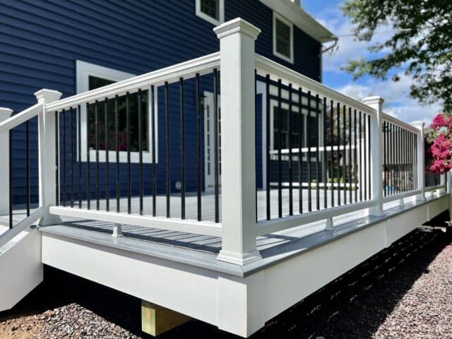 deck railing style that features white composite deck posts and rails and black metal balusters