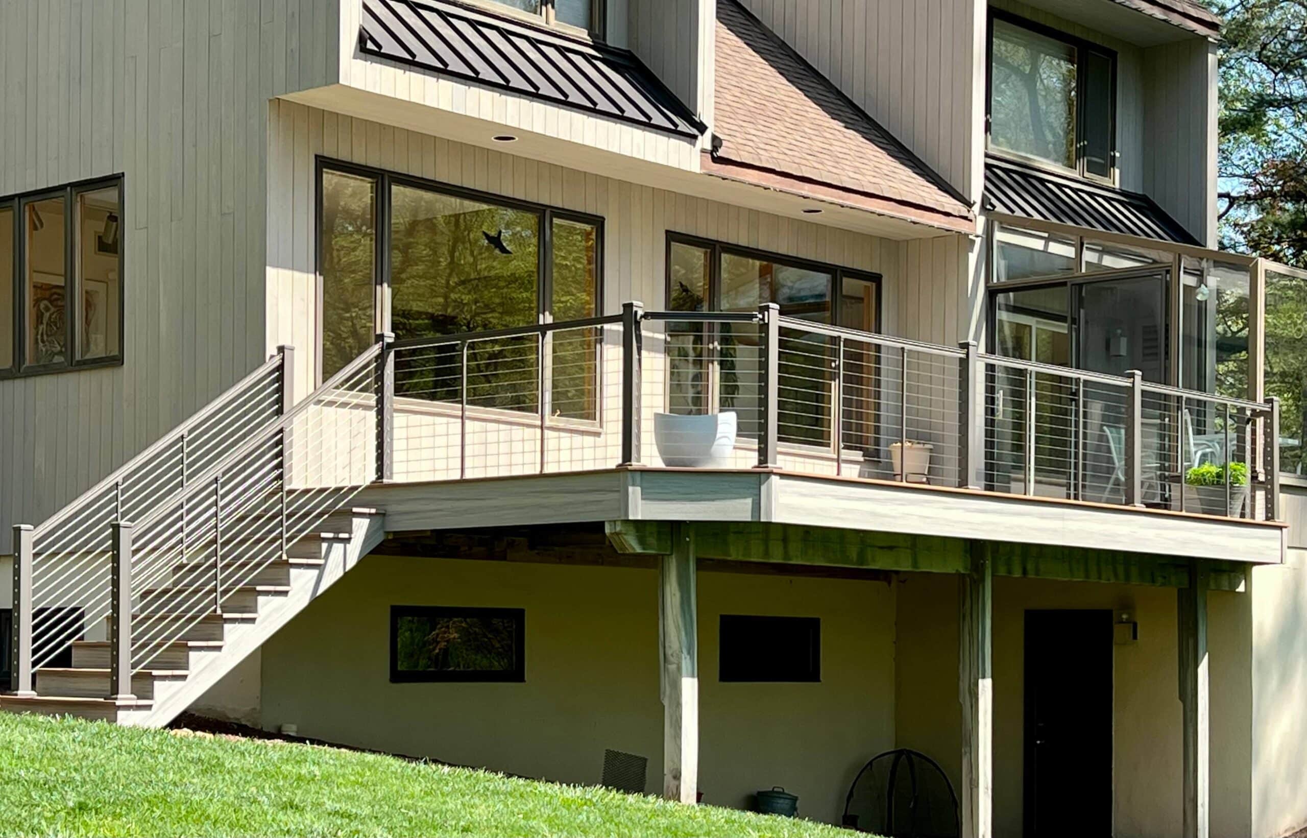 Modern deck with sleek cable railing overlooking a lush, green wooded backyard - Cable railing ideas - cable deck railing