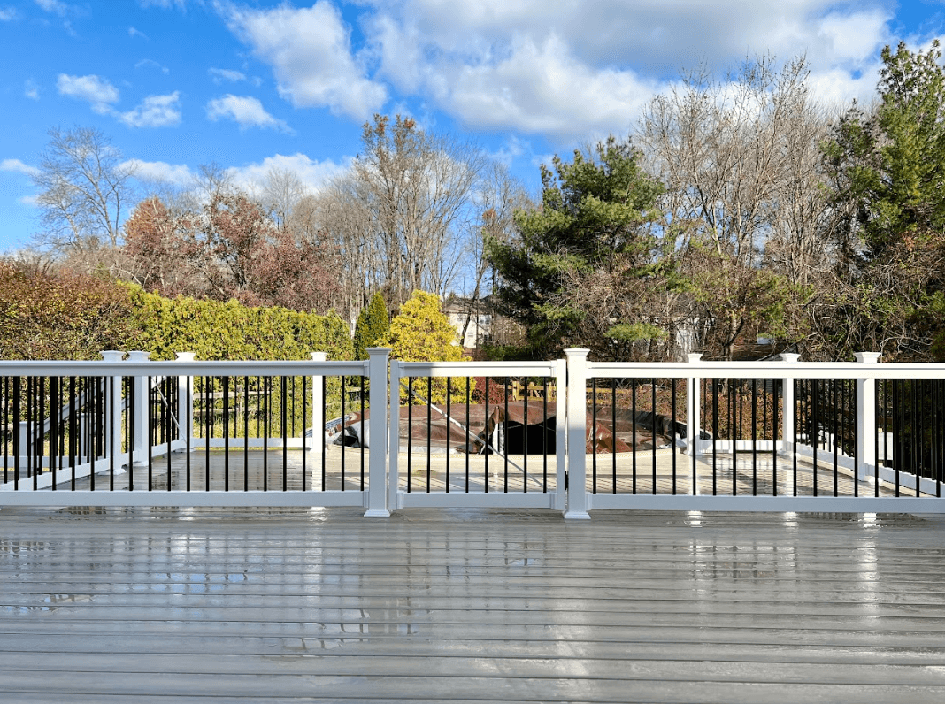 photo of a curved pool deck with deck railing and a gate - above ground pool with deck ideas